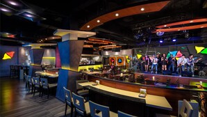 A modern restaurant with a bar area, multiple seating options, and a stage for live performances.