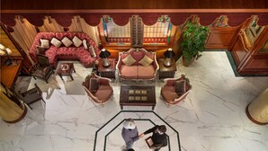 A spacious lobby with a large seating area, a central table, and a decorative plant.