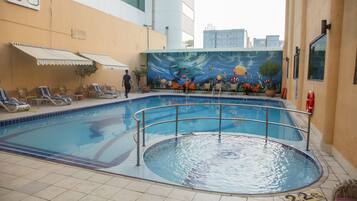 Una piscina al aire libre, sillones reclinables de piscina