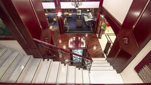 A staircase leading to a lounge area with a chandelier, seating, and a view of bicycles in the background. - Riviera Hotel Dubai (Dubai)