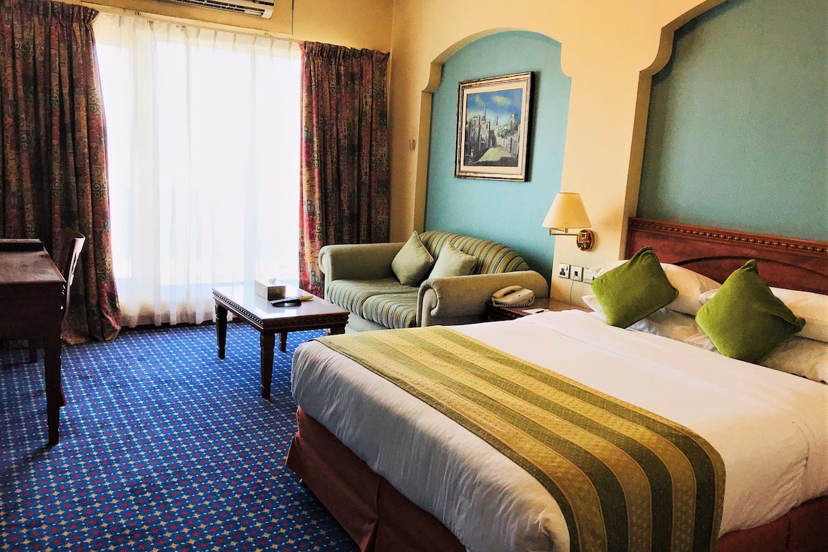 Una habitación de hotel con una cama grande, un sofá, un escritorio y una silla.