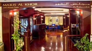 A hotel lobby with a wooden reception desk, seating area, and potted plants. - Riviera Hotel Dubai (Dubai)
