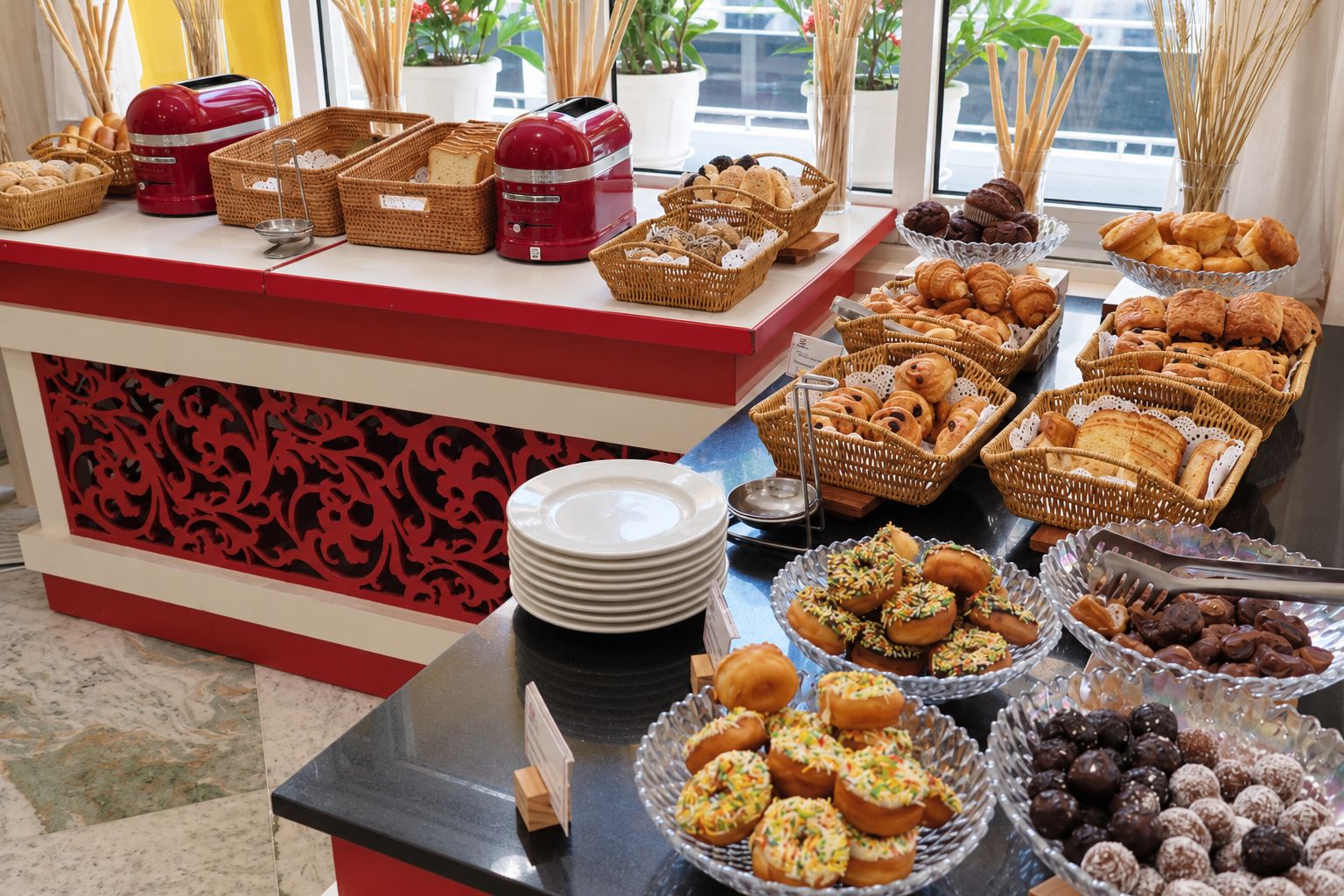 Un buffet garni de diverses pâtisseries et un appareil électroménager rouge posé sur le comptoir.