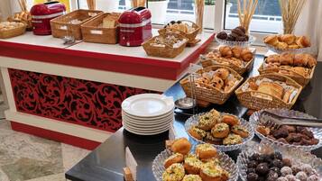 Un buffet garni de diverses pâtisseries et un appareil électroménager rouge posé sur le comptoir.