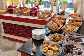 A buffet spread with various baked goods and a red appliance on the counter. - Riviera Hotel Dubai (Dubai)
