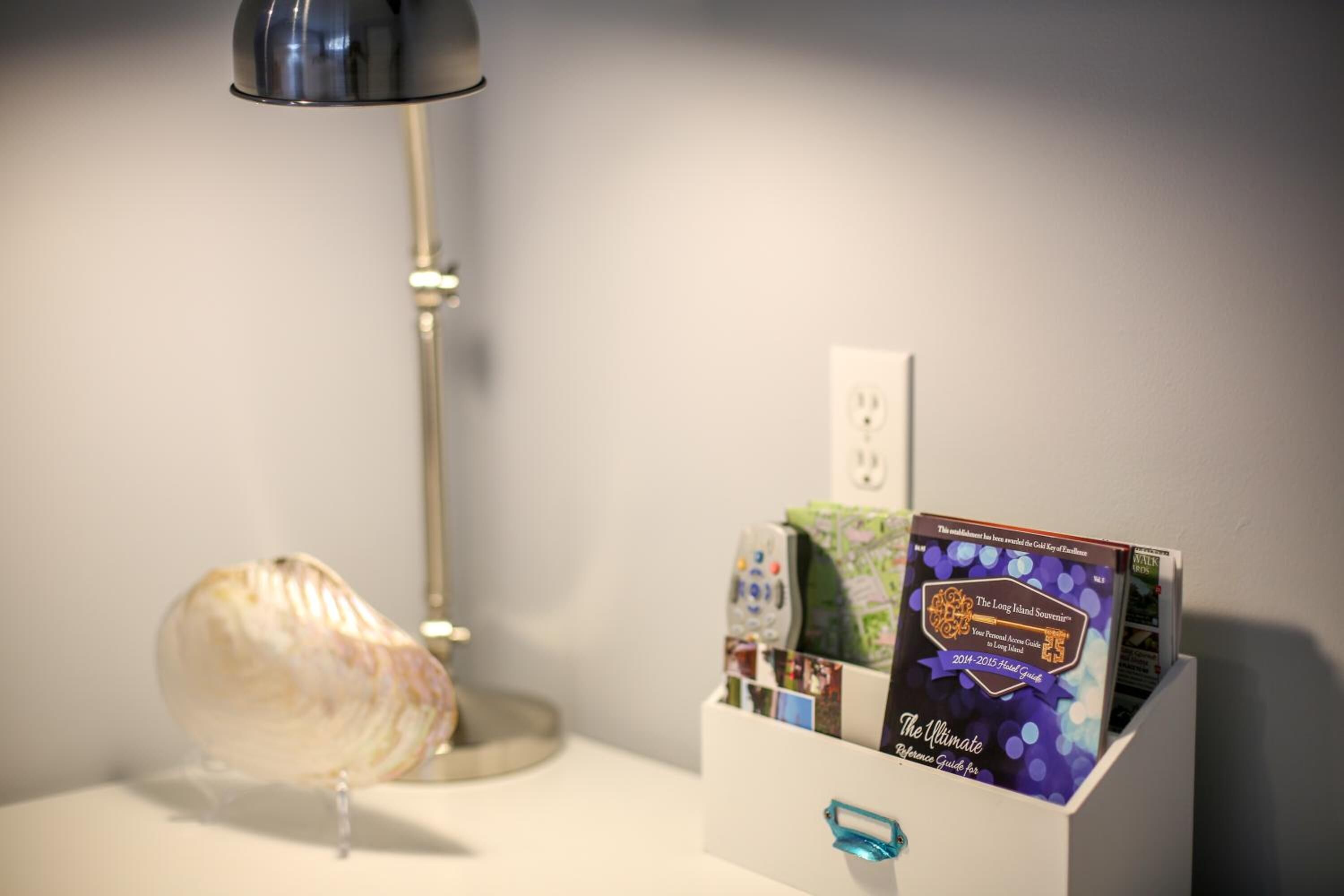 A desk with a lamp, a shell, and a magazine rack with a book titled "The Ultimate Reference Guide for 2014-2015 Long Haul."