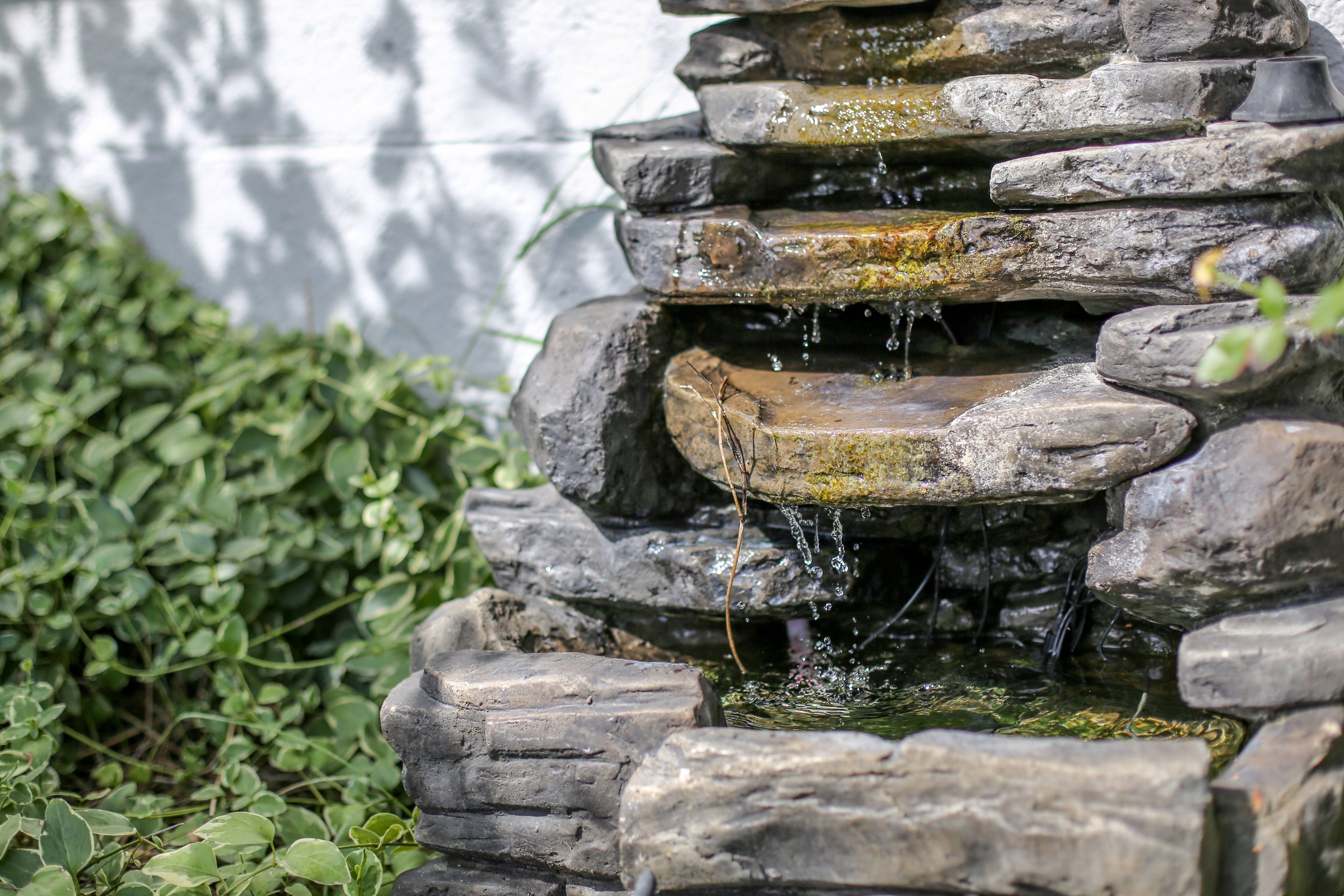 A stone water feature with cascading water, surrounded by greenery.