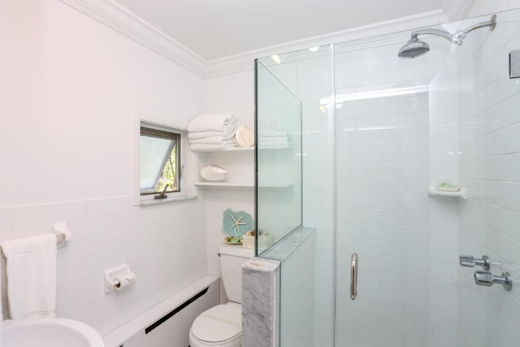 A modern bathroom with a glass shower enclosure, a toilet, and a vanity with a mirror.