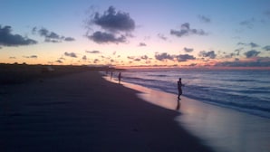 A beach scene with a sunset, calm sea, and a few people fishing. - Hamlet Inn (Southampton)