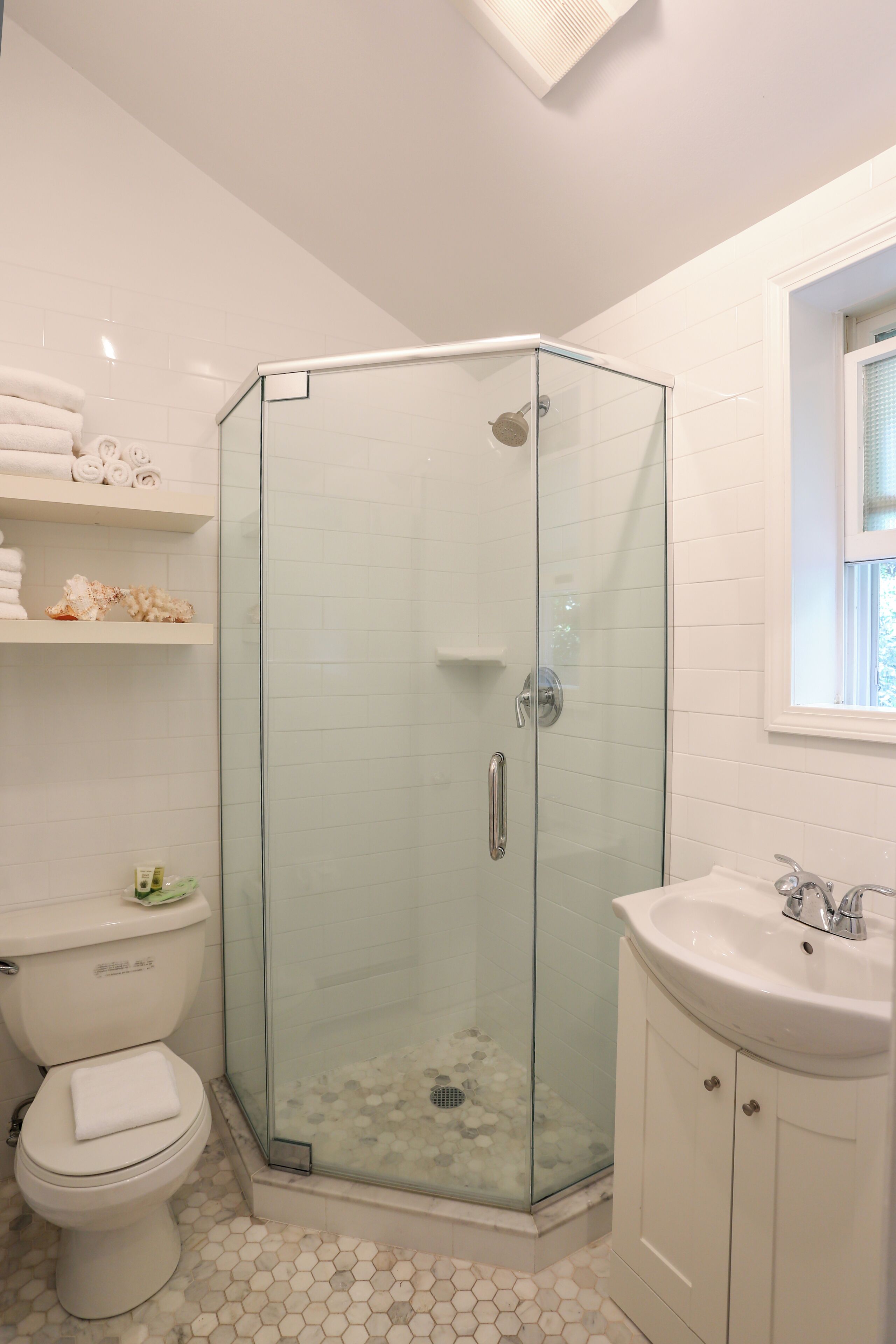 A bathroom with a glass-enclosed shower, a toilet, and a sink.