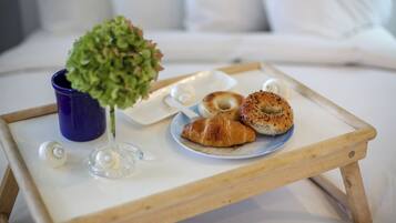 Ein Tablett mit Croissants und einer kleinen Pflanze auf einem Bett.