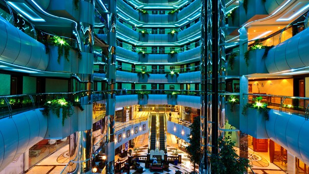 A multi-level atrium with a central staircase, glass railings, and greenery. - Emirates Concorde Hotel & Suites (Dubai)