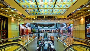 A multi-level shopping mall with escalators, glass railings, and a central atrium with seating areas. - Emirates Concorde Hotel & Suites (Dubai)