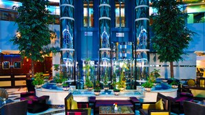 A modern lobby with a central water feature, seating areas, and potted plants. - Emirates Concorde Hotel & Suites (Dubai)