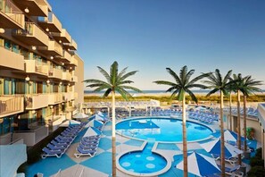 A hotel pool area with sun loungers, palm trees, and a clear view of the ocean. - Oceanfront Pan American Hotel (Wildwood Crest)