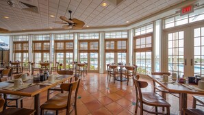 A spacious dining area with large windows, multiple tables, and chairs. - Oceanfront Pan American Hotel (Wildwood Crest)