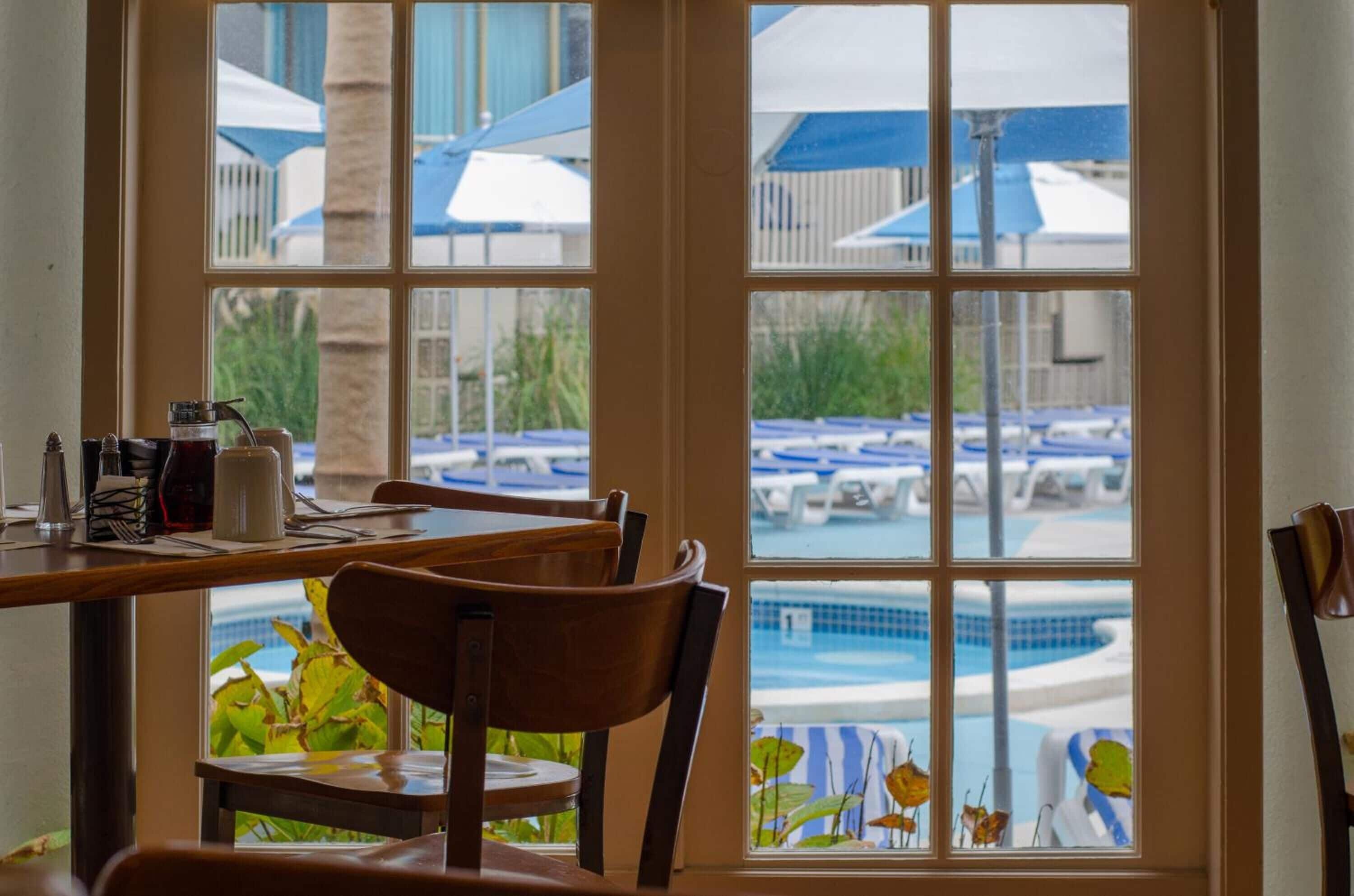 Comedor con vista a una zona de piscina, con sombrillas y sillones de descanso.