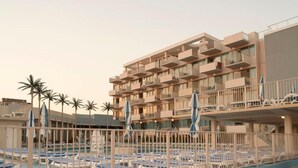 A hotel with multiple balconies, a pool area with lounge chairs, and palm trees. - Oceanfront Pan American Hotel (Wildwood Crest)