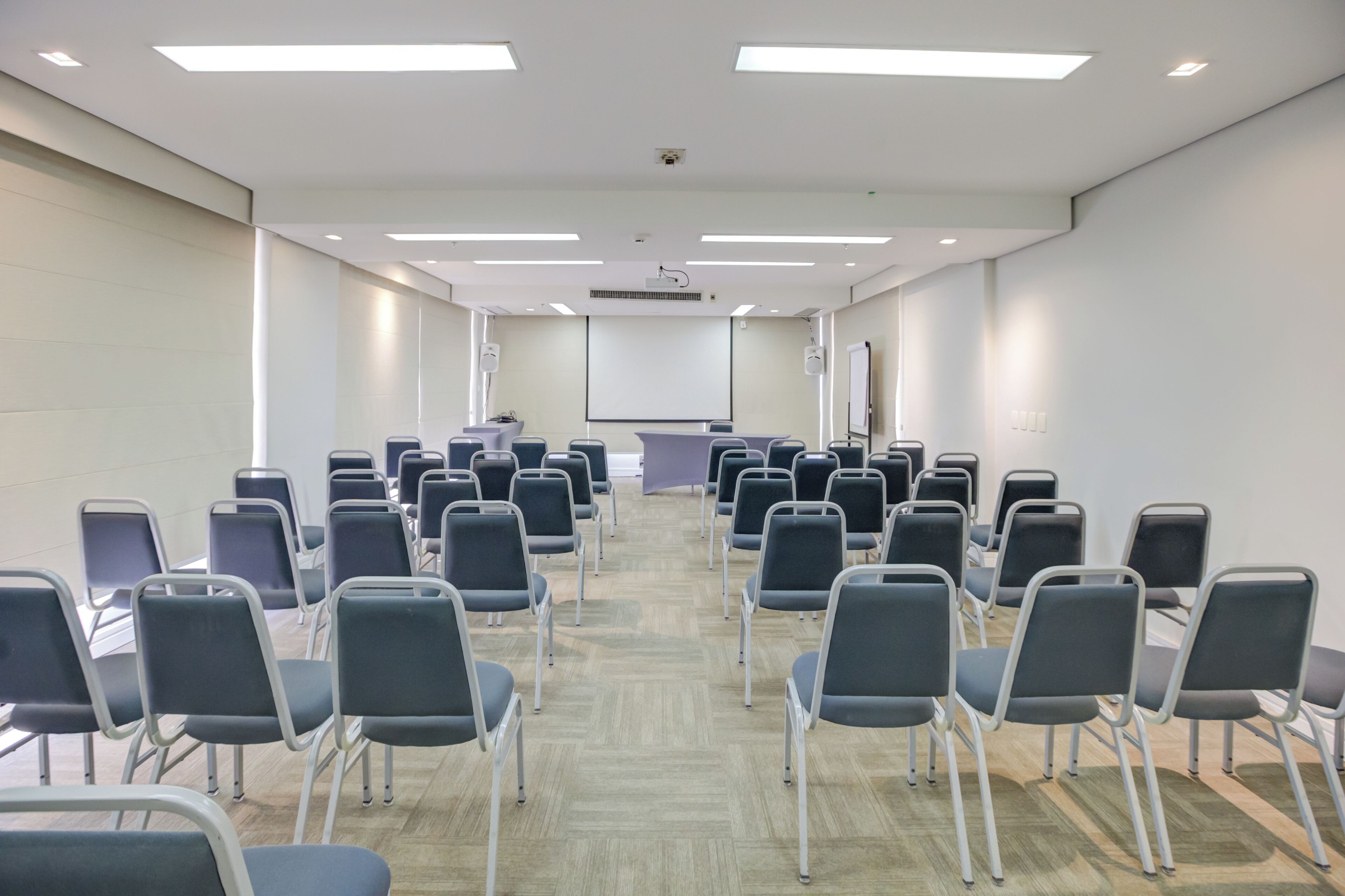 A conference room with rows of chairs, a projector screen, and a whiteboard.