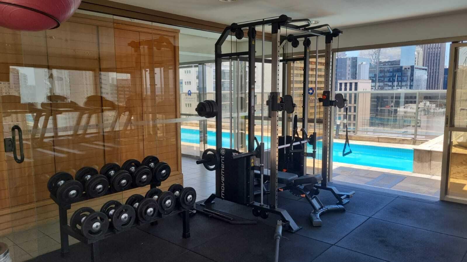 A gym with weightlifting equipment and a view of a swimming pool.