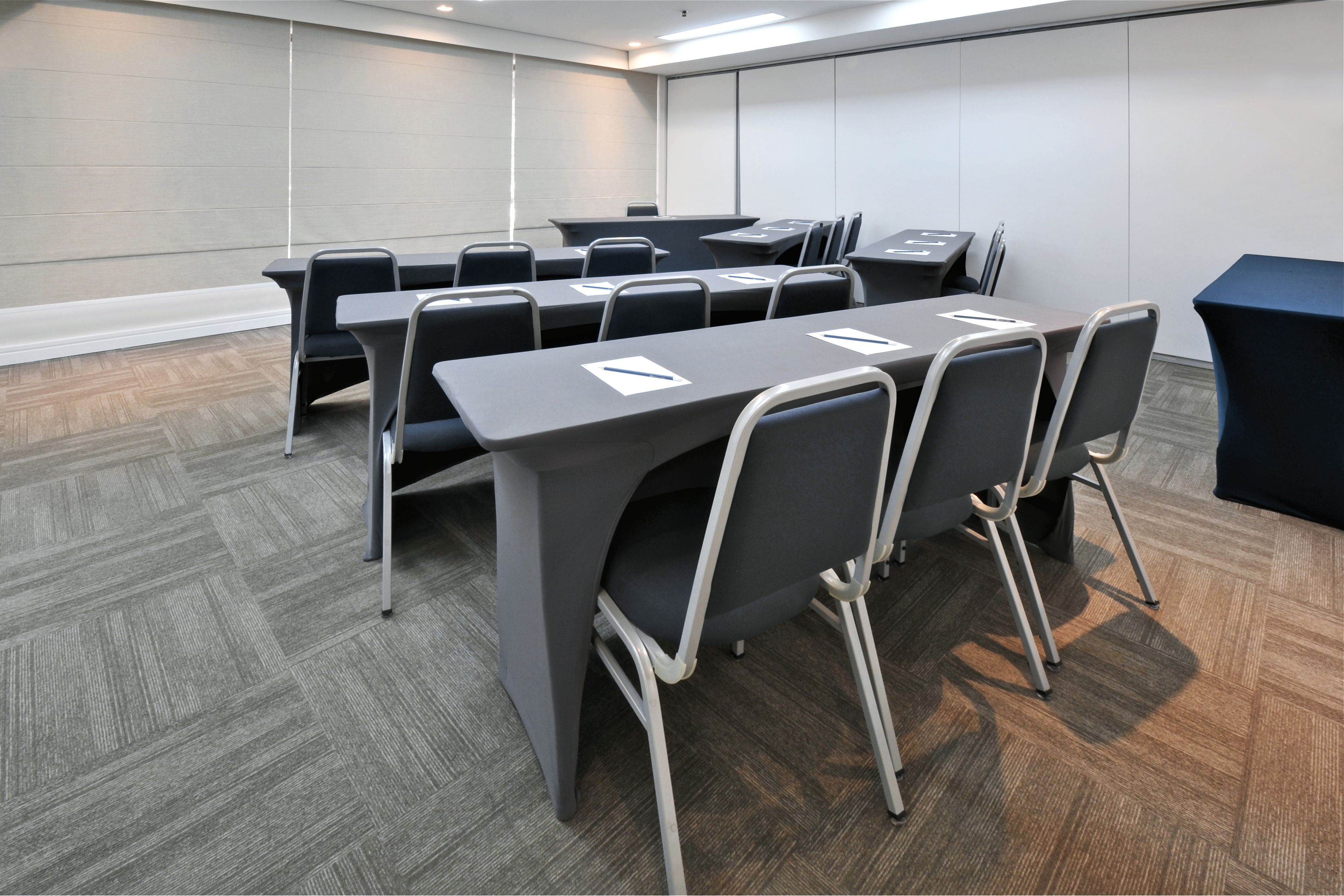 Une salle de conférence avec une longue table, de nombreuses chaises et une nappe bleu foncé.