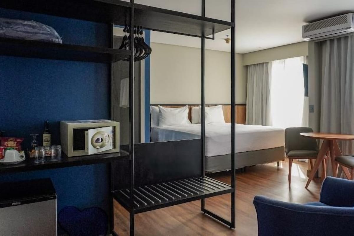 A hotel room with bunk beds, a desk, a chair, a bed, and a window with curtains.