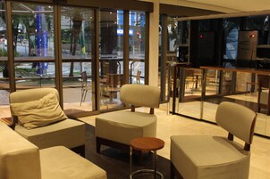 Una hall moderna con zone relax, ampie finestre e un bar.