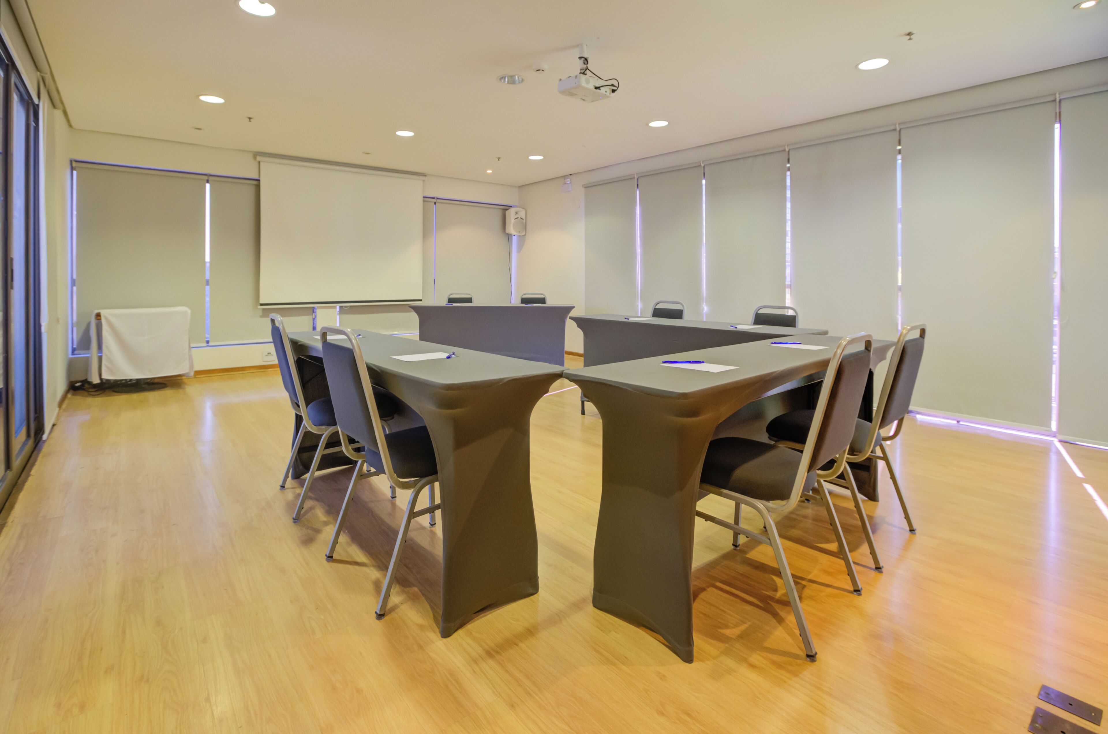 Een vergaderruimte met een lange tafel, stoelen, een beamer en een whiteboard.