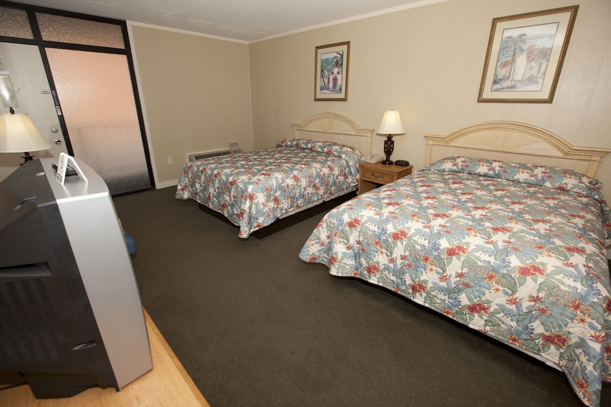 Habitación de hotel con dos camas, un escritorio con teléfono y un cuadro colgado en la pared.