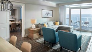 Una sala de estar moderna con un sofá, sillas, un comedor y vistas al mar.