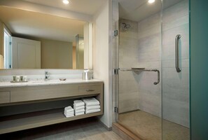 A modern bathroom with a glass-enclosed shower, a vanity with a mirror, and neatly folded towels. - Driftwood at the Boardwalk (Myrtle Beach)