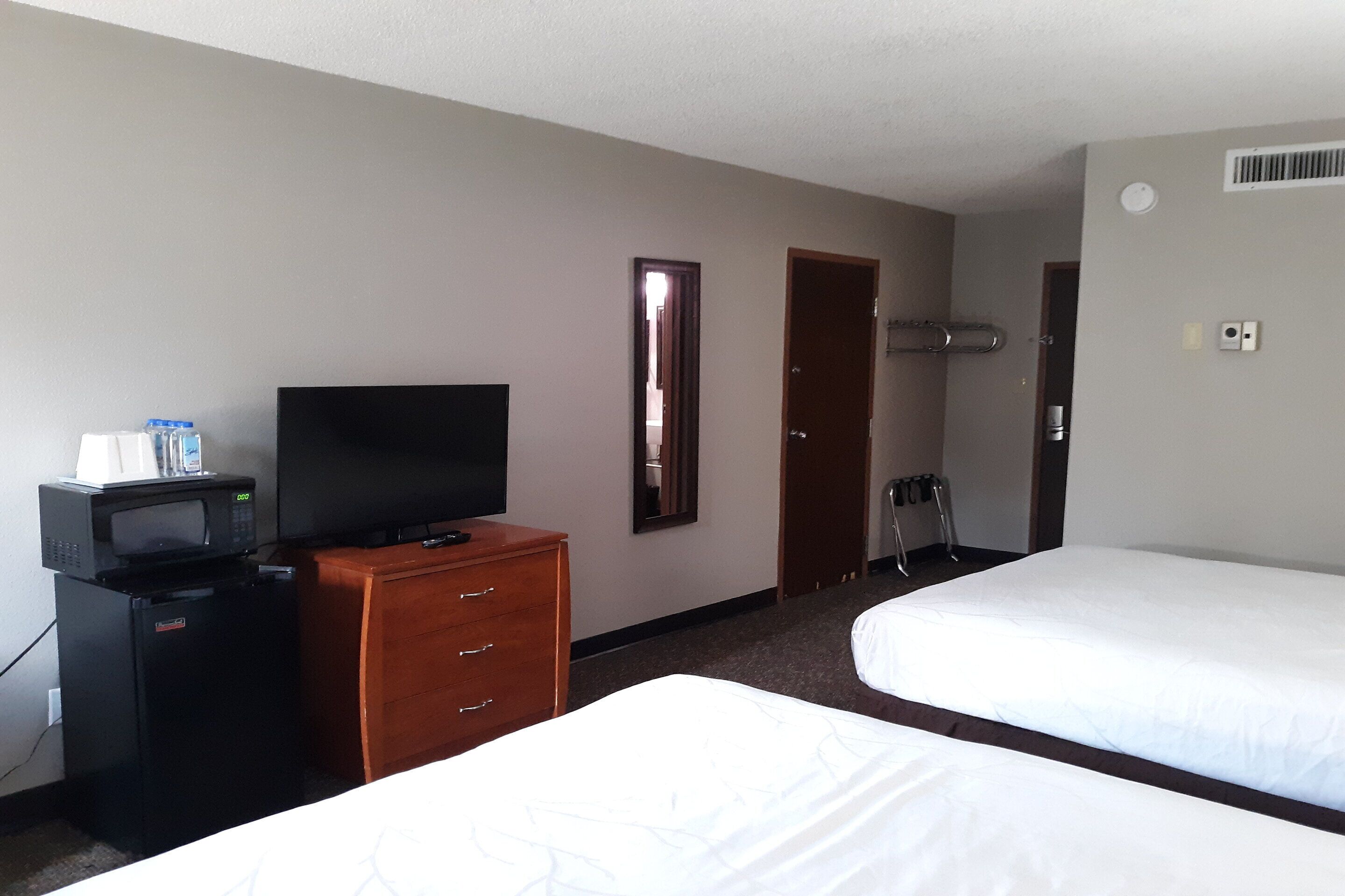 Una habitación de hotel con cama, televisor, minibar y cómoda de madera.