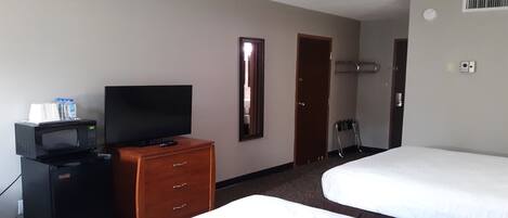 Una habitación de hotel con cama, televisor, minibar y cómoda de madera.