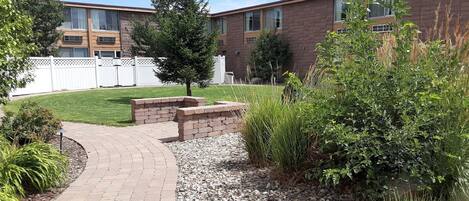 A residential building with a brick facade, a paved pathway, and a well-maintained lawn.
