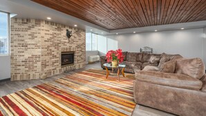 A modern living room with a brick fireplace, leather sofa, and a colorful striped rug. - The Dakota (Sioux Falls)