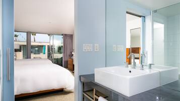 Quarto de hotel moderno com uma cama grande, banheiro com pia e espelho espaçosos, e vista para o exterior.