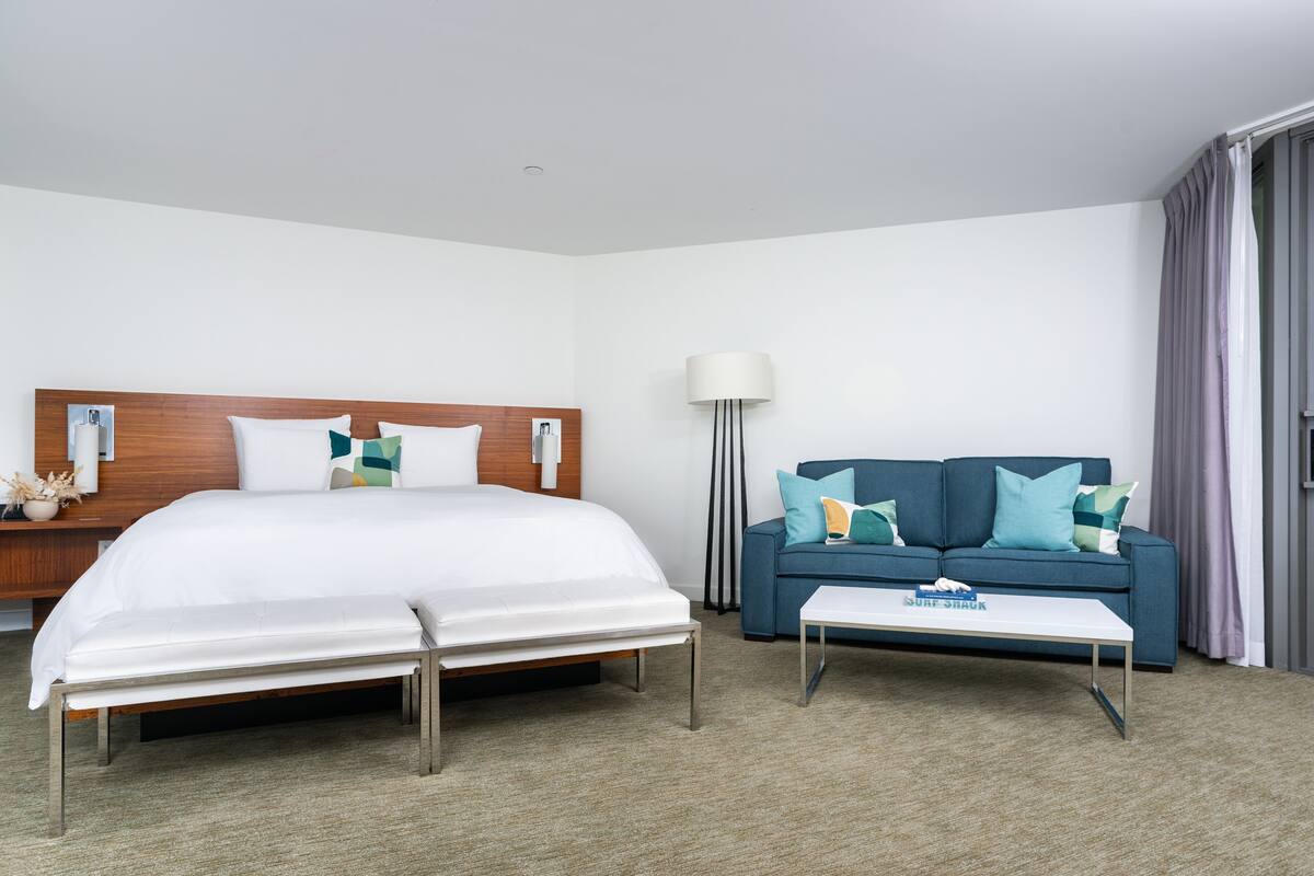 Une chambre d’hôtel avec un lit, un canapé, une table basse et une lampe.