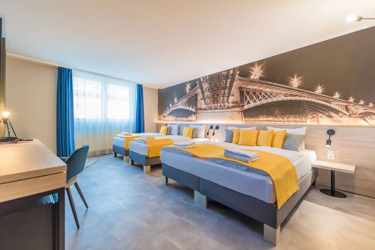 A hotel room with two beds, a desk, and a large mural of the Eiffel Tower.
