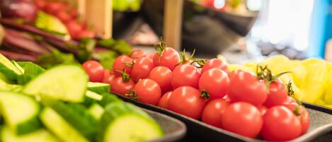 Verschiedene frische Gemüsesorten, darunter Tomaten und Gurken, werden auf Tabletts präsentiert.