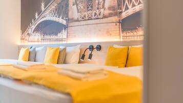Una habitación de hotel con una cama, almohadas y una lámpara fijada a la pared.