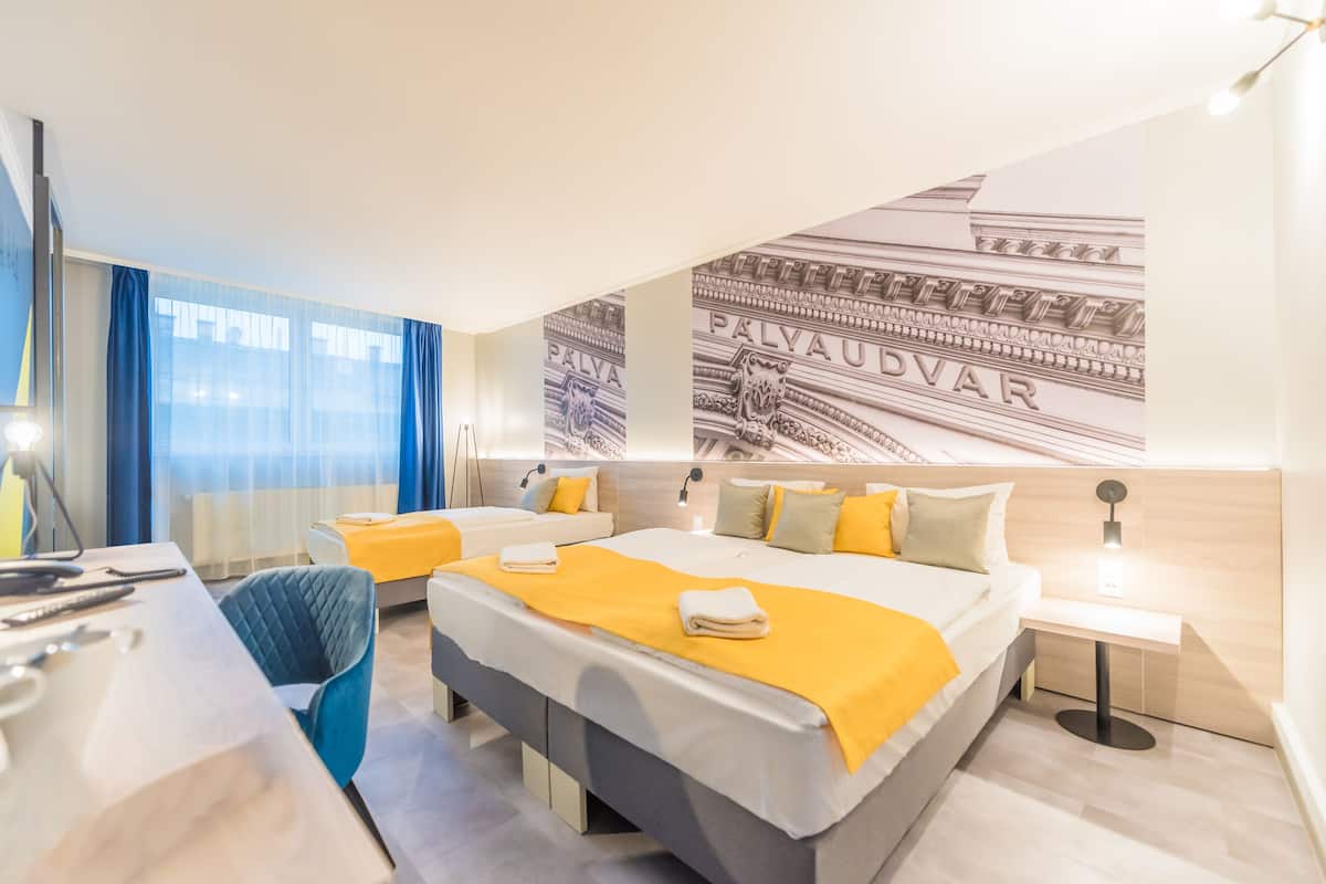A modern hotel room with a large bed, two bedside tables, a desk, and a chair.