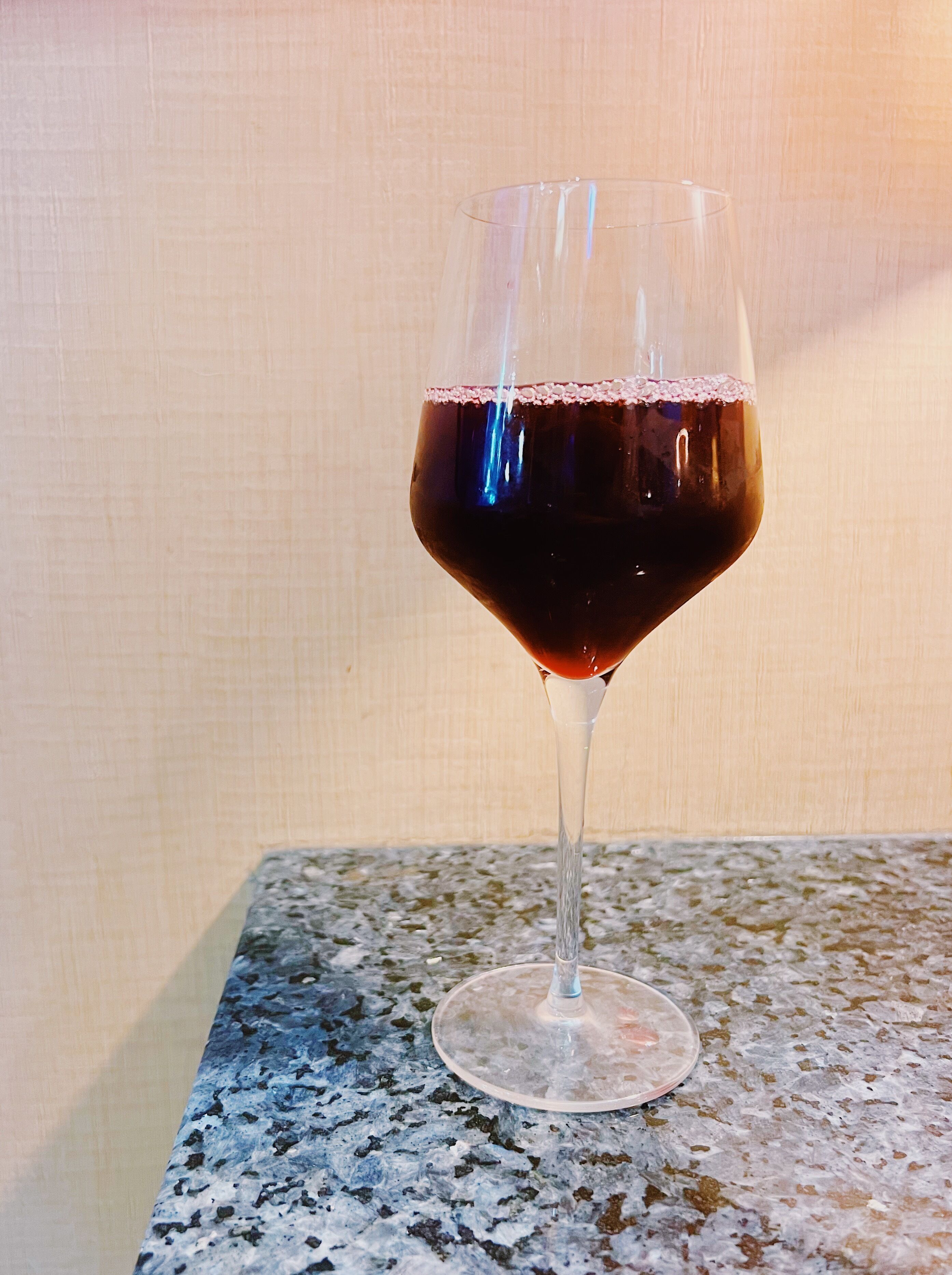 A glass of red wine on a granite countertop.