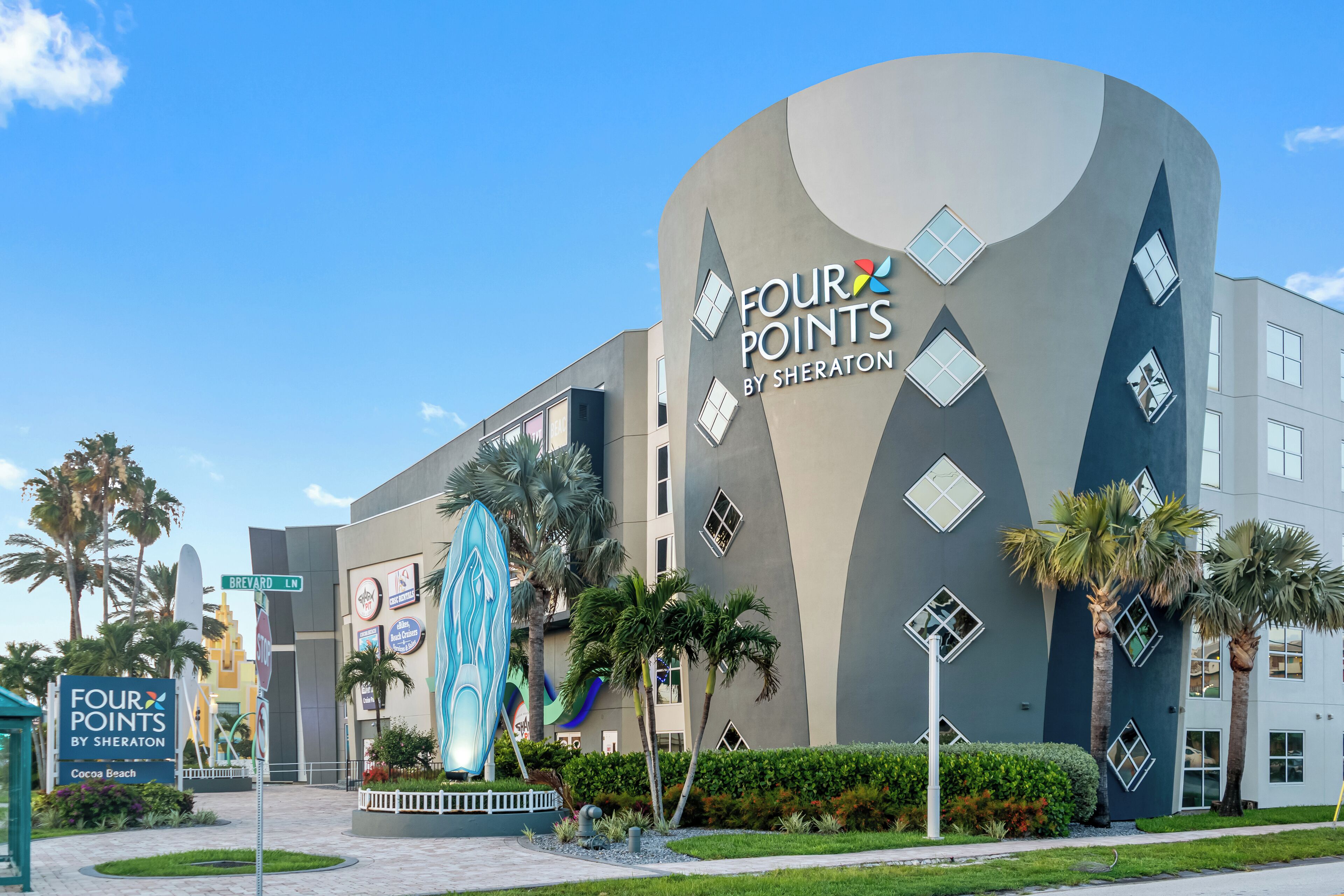 Un edificio moderno con una fachada curva distintiva y un gran letrero de 'Four Points by Sheraton' en Cocoa Beach.