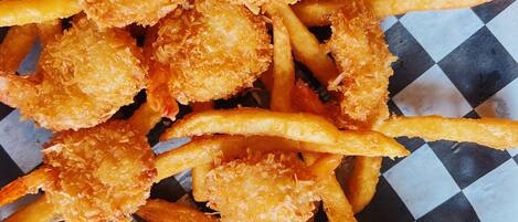 A basket of golden-brown fries and breaded fish, accompanied by a small container of ketchup and a side of coleslaw.