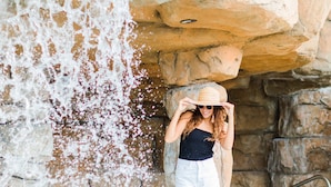 A person standing near a water feature with a stone wall and a metal railing.