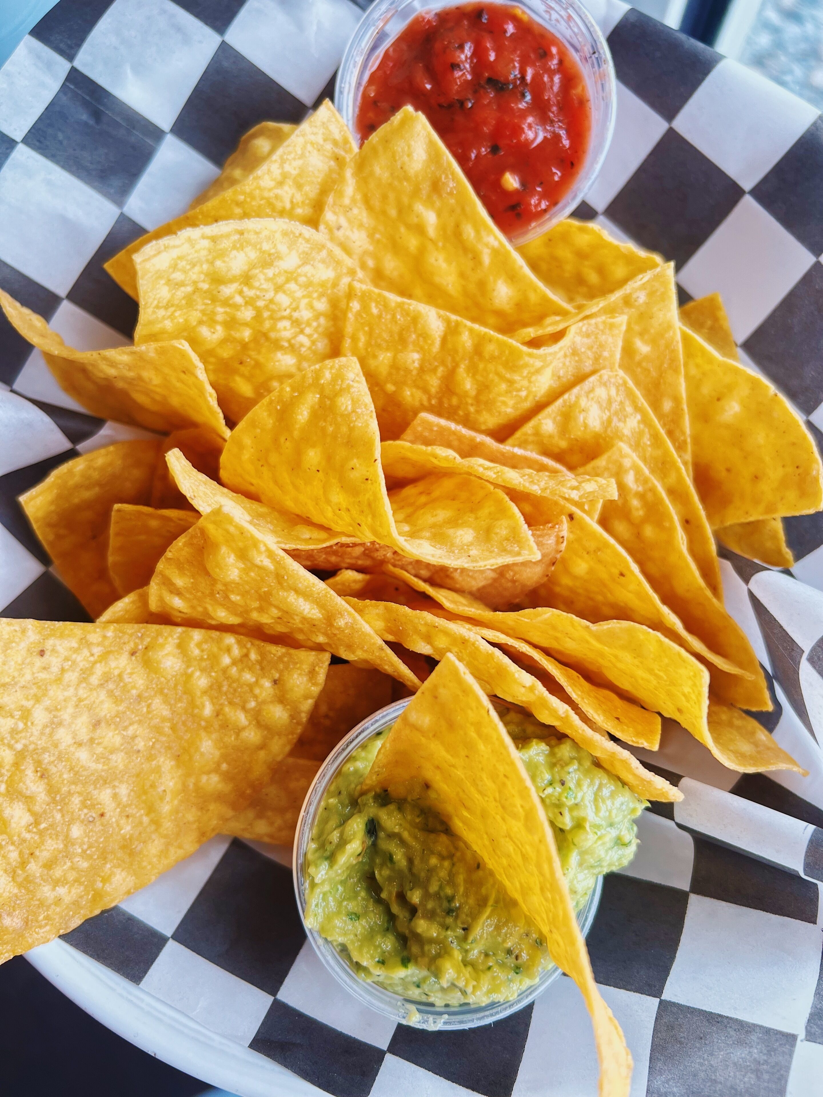 Eine Schüssel Tortilla-Chips mit zwei kleinen Schalen Salsa und Guacamole.