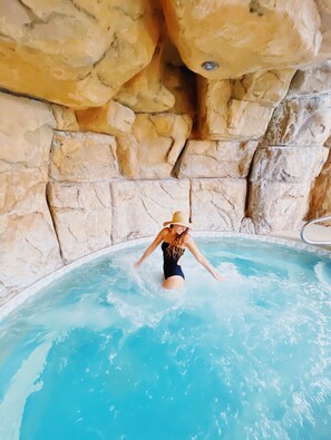 Une personne dans une piscine, avec un mur rocheux en arrière-plan.