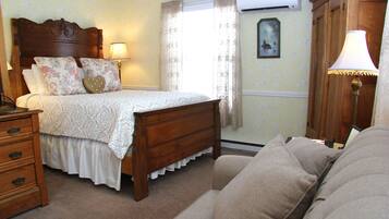 A bedroom with a wooden bed, a nightstand, a dresser, a lamp, and a window with curtains.