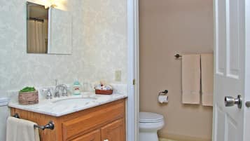 A bathroom with a wooden vanity, a mirror, a sink, and a toilet.