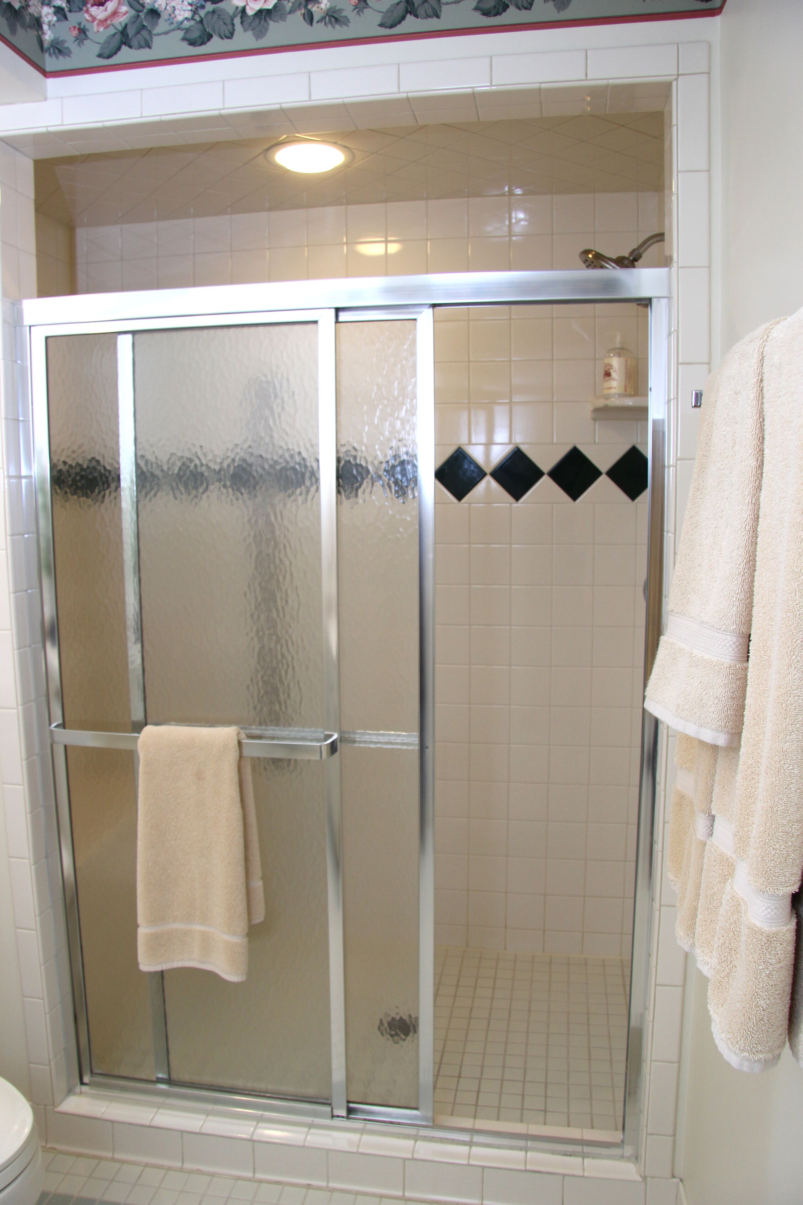 A glass-enclosed shower stall with a towel hanging on the door.